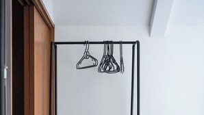Una habitación con un armario de madera, estructura de cama metálica y un perchero.