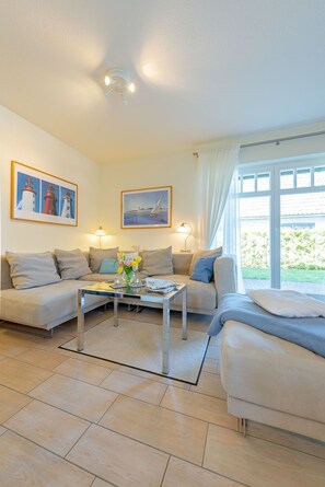 Ein Wohnzimmer mit zwei Sofas, einem Couchtisch und einem Fenster mit Vorhängen.