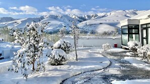 Eine verschneite Landschaft mit einem Gebäude mit Glasfassade, blauem Himmel und schneebedeckten Bäumen.