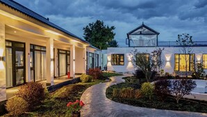 Ein modernes Hotel mit überdachtem Außenbereich, einem Gartenweg und einer gläsernen Überdachung.