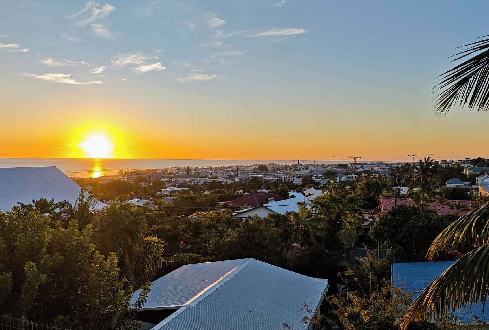 A coastal town at sunset with visible buildings and a clear sky.