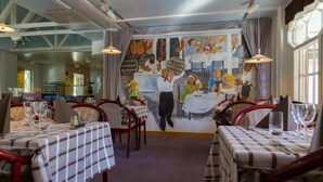 A restaurant with tables set for dining, a mural on the back wall, and a view of the dining area. - Hotell Cikada (Mariehamn)