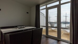 Una habitación moderna con una mesa de comedor, sillas y un ventanal con vistas a un puerto deportivo.
