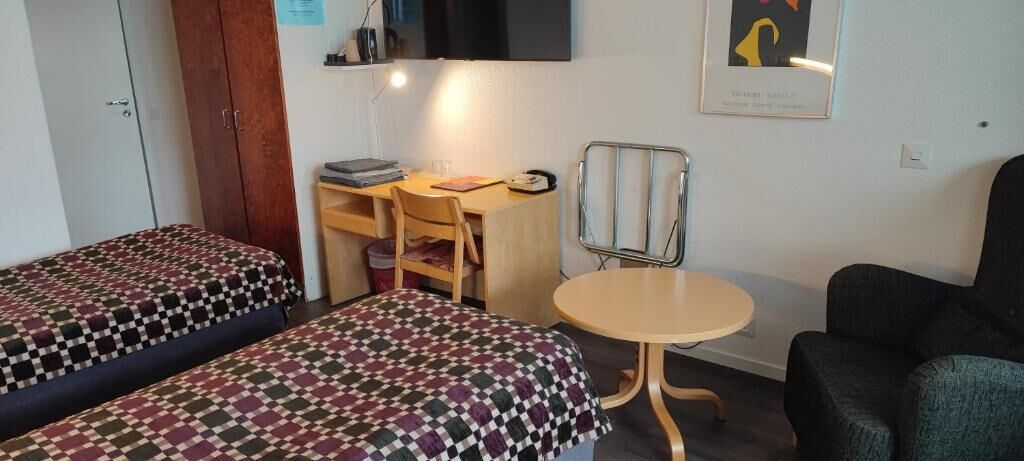 Ein Zimmer mit zwei Betten, einem Schreibtisch, einem Stuhl und einem kleinen Tisch.