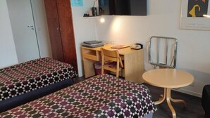 Una habitación con dos camas, un escritorio, una silla y una mesita.