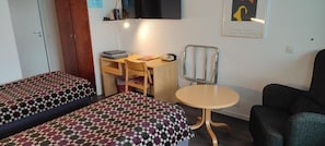 Ein Zimmer mit zwei Betten, einem Schreibtisch, einem Stuhl und einem kleinen Tisch.