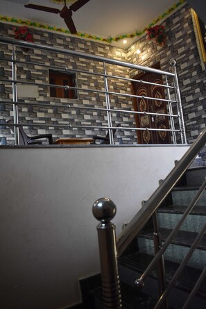 Eine Treppe mit Metallgeländer, einem Deckenventilator und einer Wand mit dekorativem Muster.