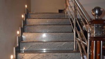 A staircase with marble steps, metal railings, and a wooden handrail.