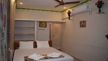 A bedroom with a bed, ceiling fan, air conditioning unit, and decorative wall elements.