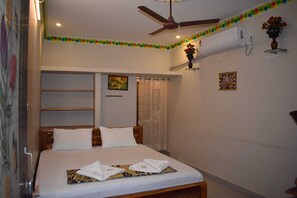 Ein Schlafzimmer mit Bett, Deckenventilator, Klimaanlage und dekorativen Wandelementen.