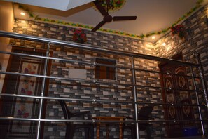 Eine Treppe mit Metallgeländer, einem Deckenventilator und einer Steinwand mit floralem Dekor.