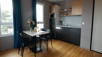 Una cucina moderna con mobili scuri, un forno a microonde e un lavello. C'è un tavolo da pranzo con sedie e un vaso di fiori.