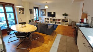Ein modernes Wohnzimmer mit rundem Tisch, Sofas, einem Fernseher und einem Bücherregal.