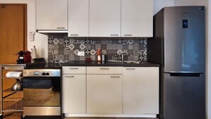 Eine moderne Küche mit weißen Schränken, einem Edelstahl-Kühlschrank und Fliesen mit Muster.