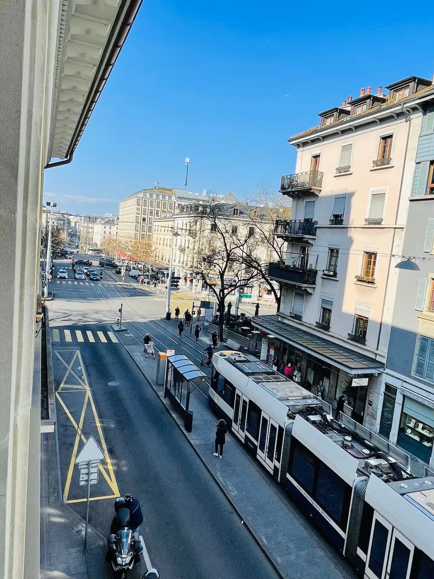 A street view with a tram, pedestrians, and buildings.