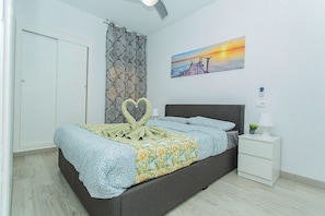 Ein Schlafzimmer mit einem Bett, einem Nachttisch, einem Gemälde und einem gemusterten Vorhang.