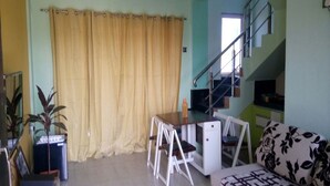 A room with a desk, chairs, a sofa, a staircase, and a plant. - White Sand Retreat (Guhagar)