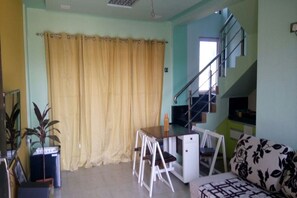 A room with a desk, chairs, a sofa, a staircase, and a plant. - White Sand Retreat (Guhagar)