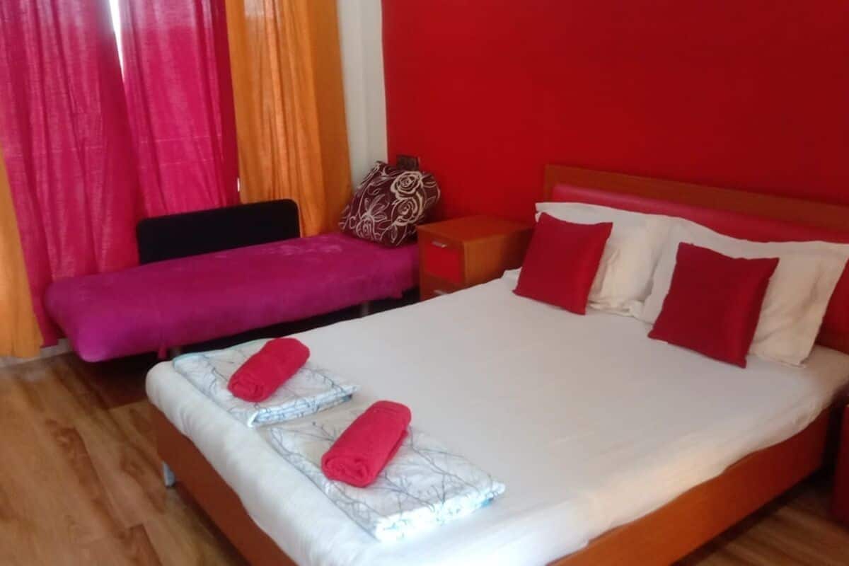 A hotel room with a bed, a nightstand, a bedside table, and a window with curtains.