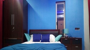 A bedroom with a bed, a wardrobe, a nightstand, and a mirror. - White Sand Retreat (Guhagar)