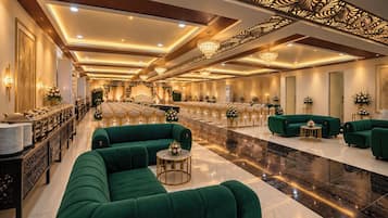 Une grande salle avec des rangées de chaises, une scène et des canapés verts.