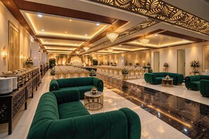 A spacious hall with rows of chairs, a stage, and green sofas. - Hotel Medha Inn (Danapur)