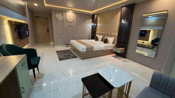 Un dormitorio moderno con cama, mesitas de noche, zona de estar y televisión.