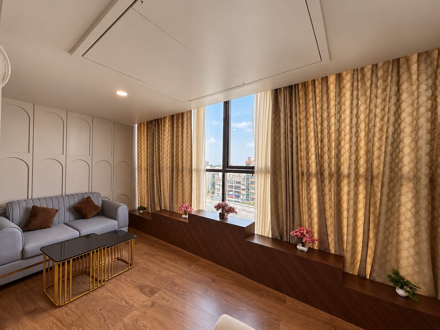 A modern living room with a sofa, a coffee table, and a view of the city through large windows.