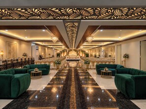 A hotel lobby with a long reception desk, green sofas, chandeliers, and a decorative ceiling. - Hotel Medha Inn (Danapur)