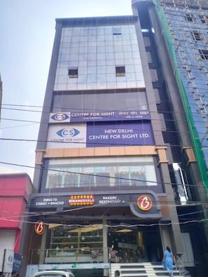 Um edifício com vários andares, com placas indicando 'Centre for Sight' e 'Bikanerwala' no andar térreo.