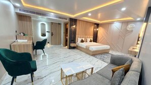 Una habitación de hotel moderna con cama, sofá, sillón y una pequeña mesa.