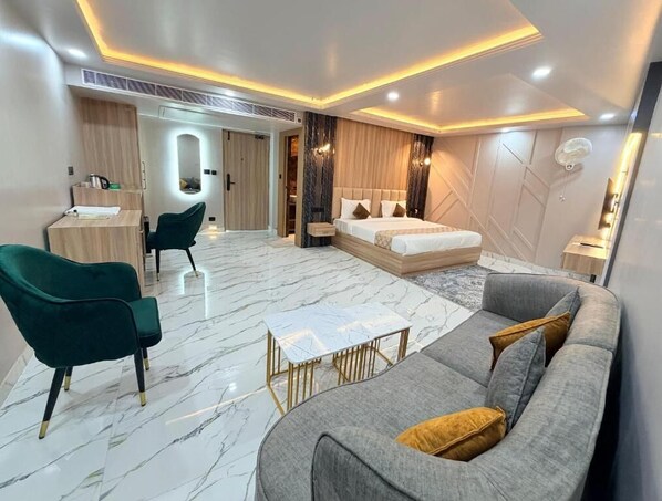 A modern hotel room with a bed, sofa, chair, and a small table. - Hotel Medha Inn (Danapur)
