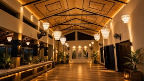 Un hall d’entrée spacieux avec un plafond haut, des lustres, des plantes en pot et des œuvres d’art accrochées aux murs.
