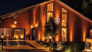 A brick building with a sign reading 'TER PALANG' at the entrance, steps leading up to the door, and a small fountain in the foreground.