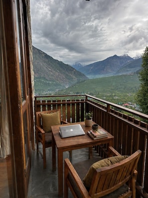 A wooden balcony with a table, chairs, and a laptop. - AKIRA BY SKYLORE (Manali)