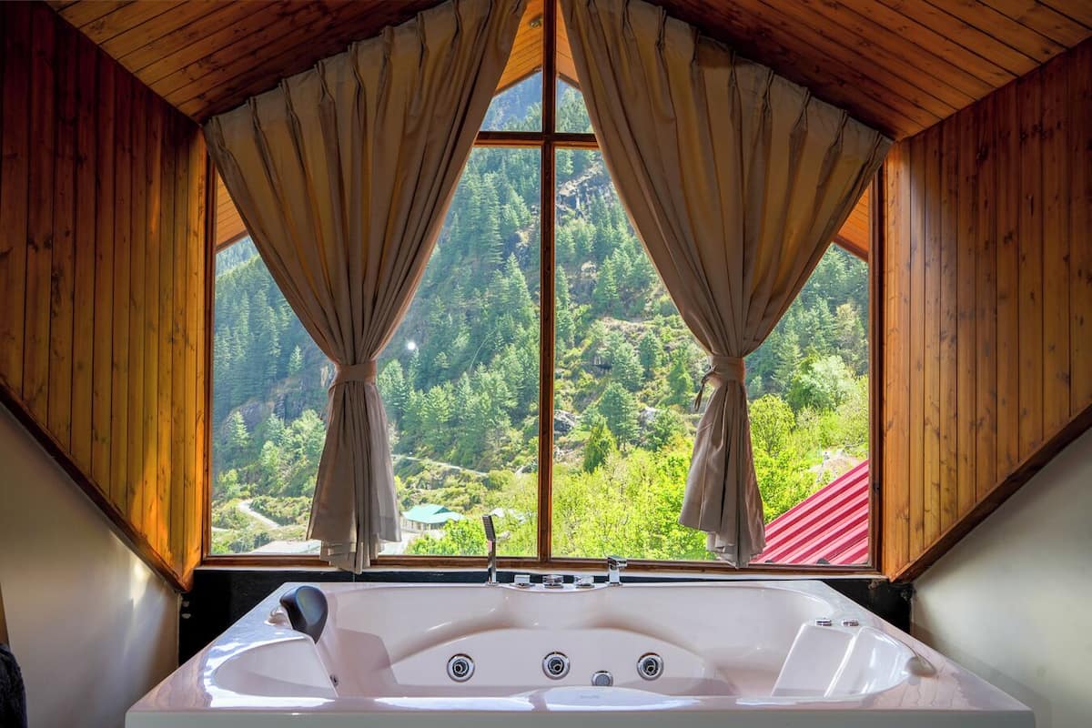 Una habitación con un ventanal grande, paredes de madera, una bañera y cortinas.