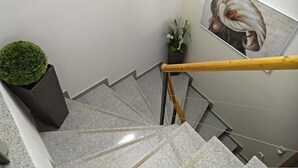 A staircase with a handrail, a potted plant, and a painting on the wall.