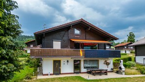 A two-story wooden house with a balcony, a small garden, and a well-maintained lawn. - Apartment 'Spatzennest' with Mountain View, Private Terrace and Wi-Fi (Arrach)