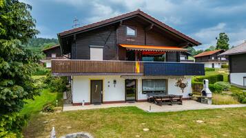 Ein zweistöckiges Holzhaus mit Balkon, kleinem Garten und gepflegtem Rasen.