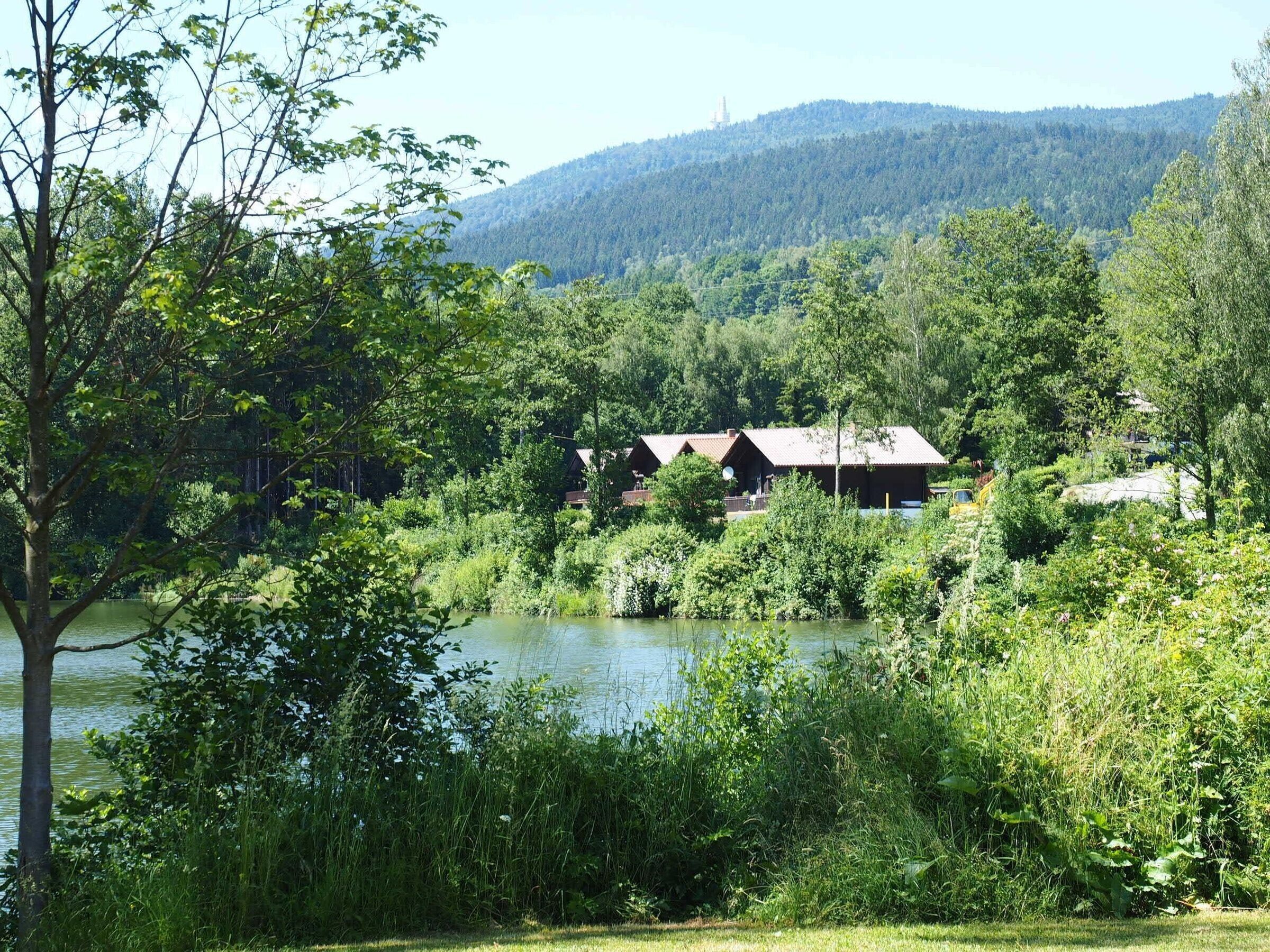 Ein Seeufer-Lodge mit rustikalen Blockhütten, umgeben von dichtem Wald und Hügeln.