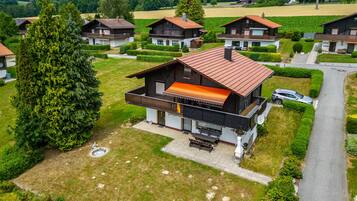 Ein modernes, zweistöckiges Haus mit Balkon, umgeben von gepflegten Gärten und freiem Blick ins Grüne.