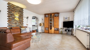 A living room with a brown leather sofa, a glass coffee table, a wooden cabinet, and a television. - Apartment 'Spatzennest' with Mountain View, Private Terrace and Wi-Fi (Arrach)