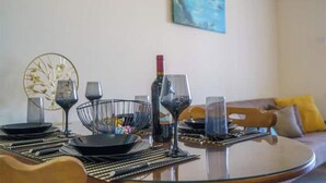 Een eettafel gedekt met borden, glazen en een wijnfles, omringd door stoelen en een decoratieve metalen schaal.