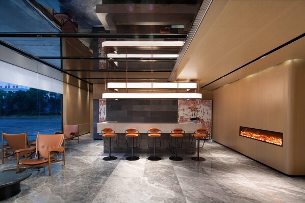 Zona de bar moderna con una barra larga, cinco taburetes y una chimenea empotrada.