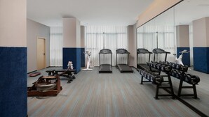 Un gimnasio con cintas de correr, elípticas y máquinas de pesas.