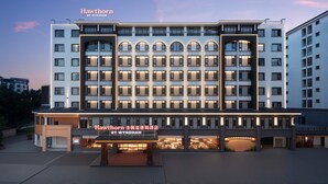 Un hotel de varios pisos con una entrada destacada, ventanas amplias y un cartel que indica que es un establecimiento Wyndham.