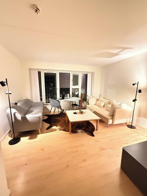 A modern living room with a sofa, a coffee table, and a dining area with chairs. - Bright Modern Apartment in City Center (Aalborg)