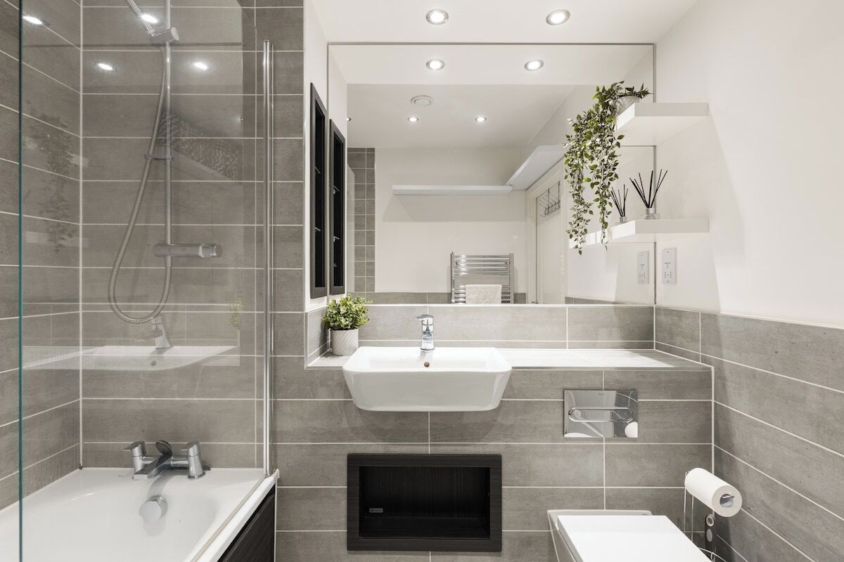Ein modernes Badezimmer mit einer Glasdusche, einem weißen Waschbecken und einer Toilette.