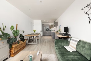 Ein modernes Wohnzimmer mit einem grünen Sofa, einem Holztisch und einem Essbereich mit einem Holztisch und Stühlen.