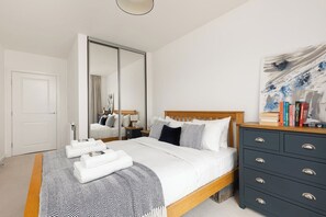 Ein Schlafzimmer mit einem Bett, einem Schminktisch, einem Spiegel und einem Bild an der Wand.